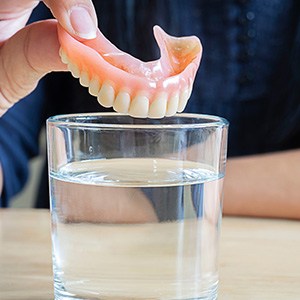 Dentures being placed in glass to soak