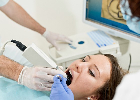 Dental team member taking digital impression of patient’s teeth