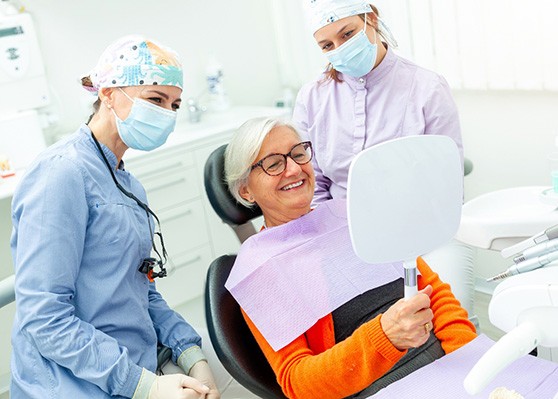 Happy senior dental patient looking in mirror