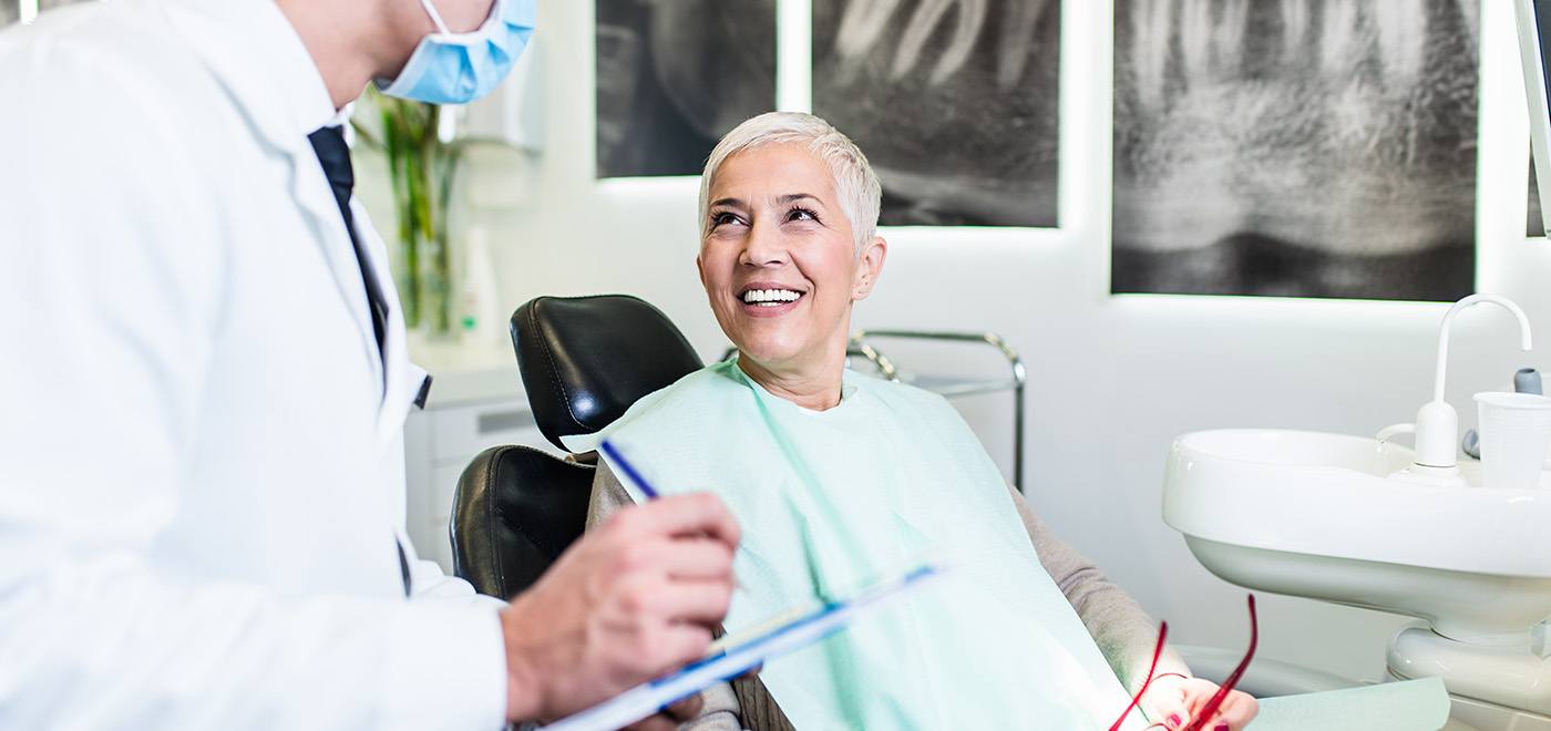 Dentist taking notes while speaking with senior patient