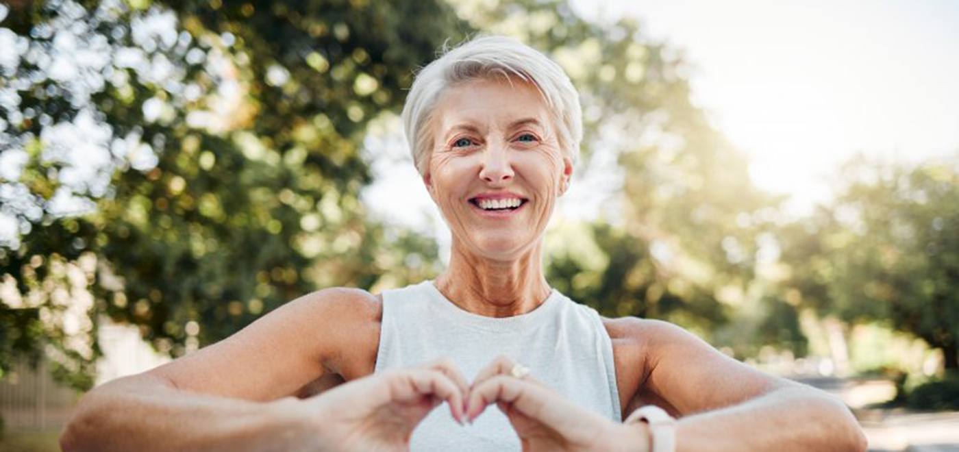 Lady smiles while making shape of heart with her hands