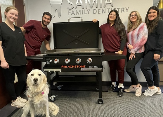 Garner dentist smiling with each arm around a Samia Family Dentistry of Garner team member
