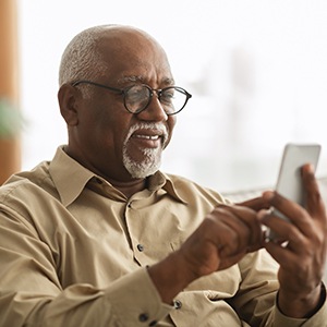 Man with glasses looking at phone at home