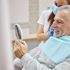 Man smiling at reflection in small, handheld mirror