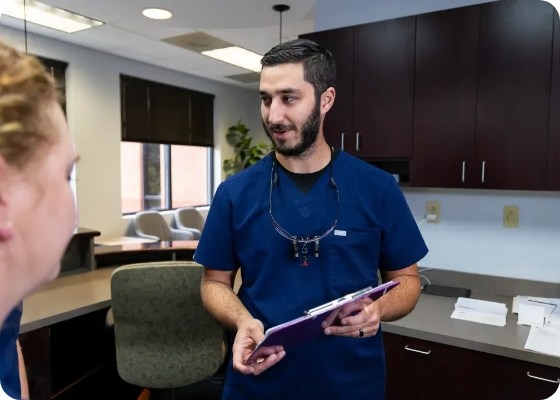 Doctor Samia holding a clipboard and talking to dental team member