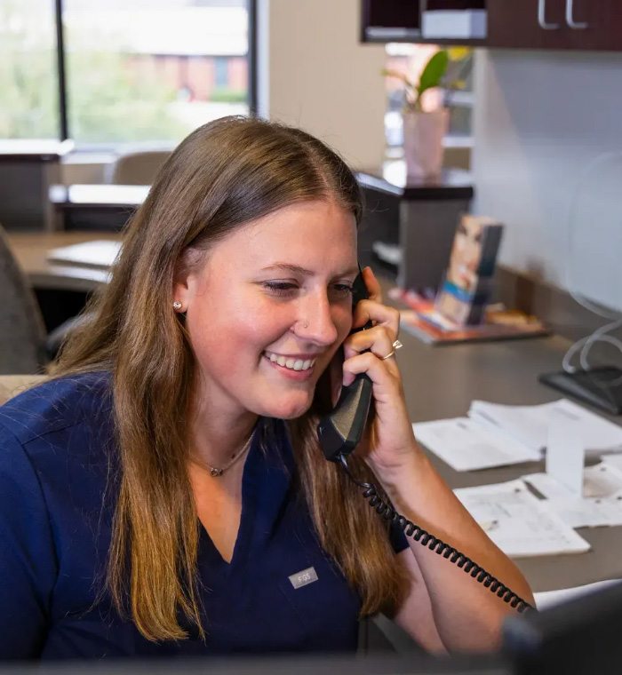 Garner dental team member smiling while answering the phone