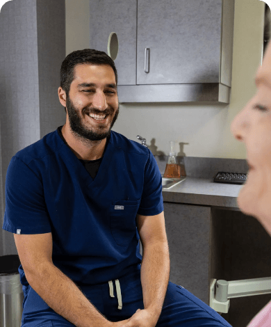 Doctor Samia smiling at a patient in the dental chair