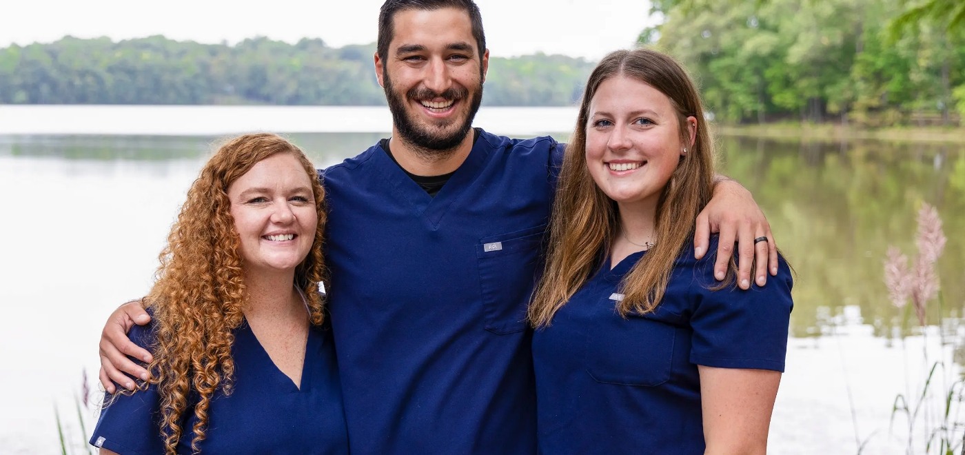 Garner dentist smiling with each arm around a Samia Family Dentistry of Garner team member