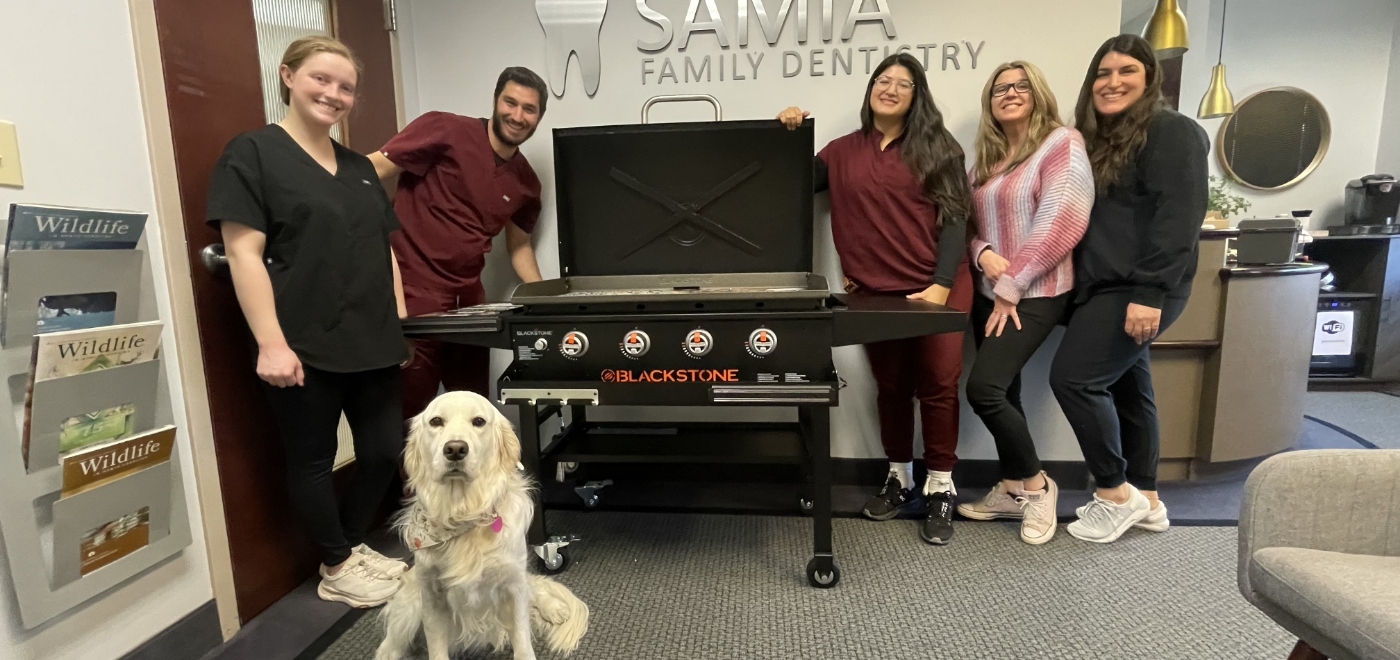 Garner dentist smiling with each arm around a Samia Family Dentistry of Garner team member