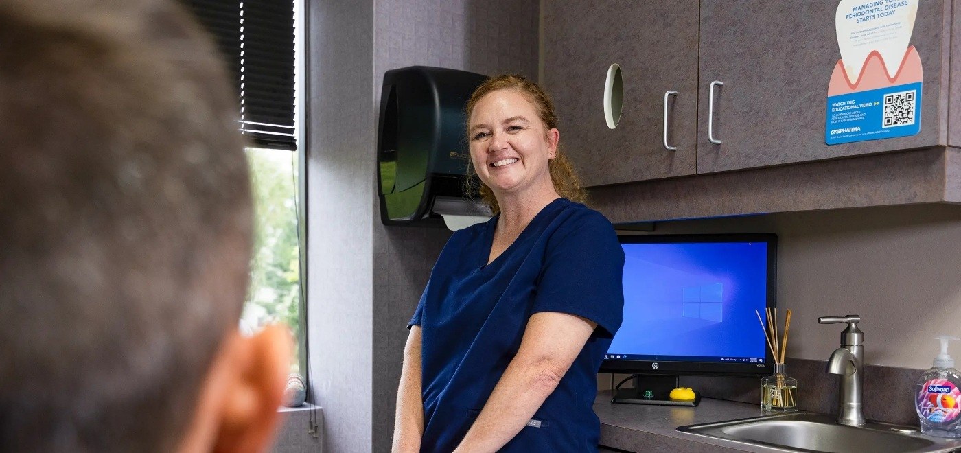 Dental team member smiling at a patient after restorative dentistry in Garner