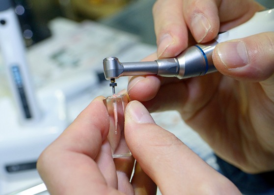 Hands demonstrating root canal technique in model block