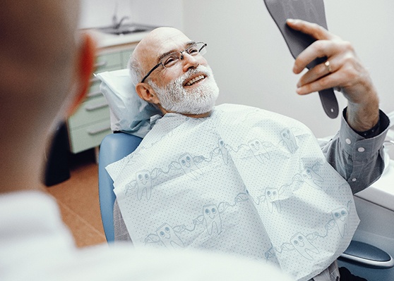 Older man with beard smiling with dentures
