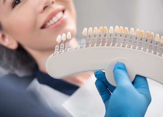 Dentist holding shade scale up to patient's smile