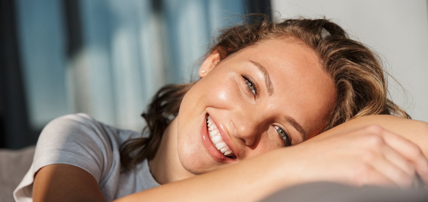 Woman leaning on cushion in the sunshine smiling