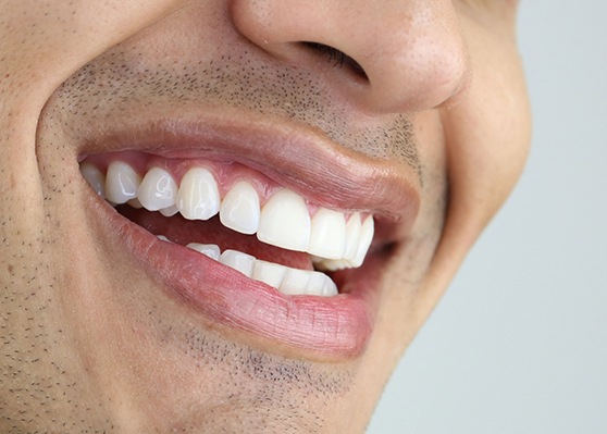 profile view closeup of man with bright white teeth smiling