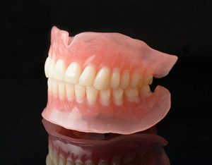 Full dentures on a reflective black surface