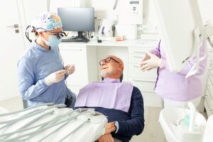 Dental team members conversing with senior patient