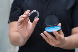 Man in black shirt holding clear aligner and case