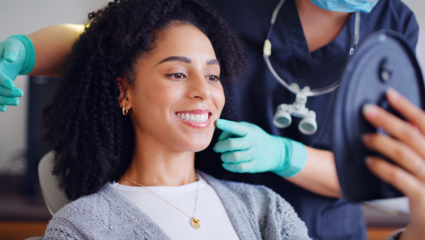 Dentist showing patient results in mirror, patient smiling with perfect teeth