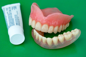Dentures sitting next to tube of denture adhesive